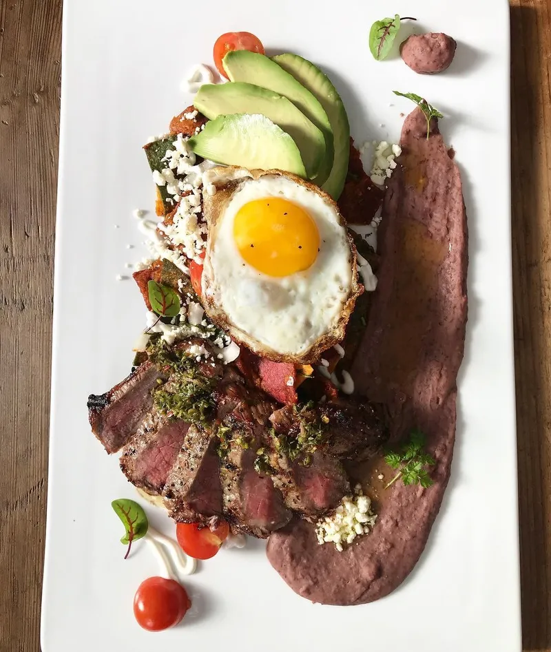 Steak and eggs with avocado, chimichurri and refried beans